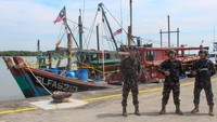 Sejumlah petugas berjaga di samping dua kapal asing berbendera Malaysia saat konferensi pers penangkapan dua kapal ikan itu diÂ Pelabuhan Bandar Deli, Belawan, Kota Medan, Sumatera Utara, Kamis (29/5/2025). (ANTARA FOTO/Fransisco Carolio)