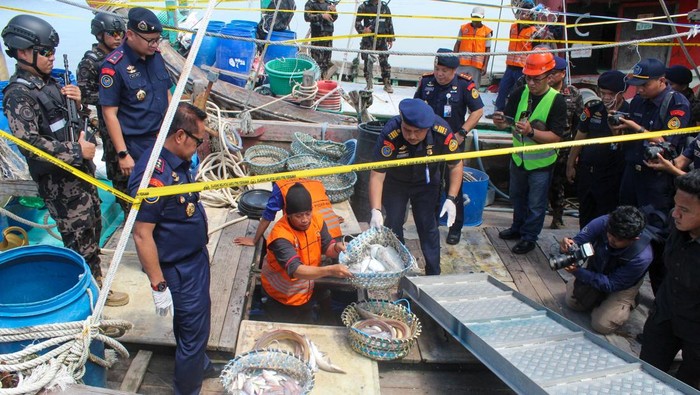 Sejumlah petugas melihat dua kapal asing berbendera Malaysia yang diamankan sebagai barang bukti di Pelabuhan Bandar Deli, Belawan, Kota Medan, Sumatera Utara, Kamis (29/5/2025). Kementerian Kelautan dan Perikanan berhasil mengamankan dua kapal ikan asing berbendera Malaysia saat melakukan penangkapan ikan secara ilegal di perairan Selat Malaka dan menangkap tujuh tersangka beserta barang bukti 300 kilogram ikan campuran. ANTARA FOTO/Fransisco Carolio/nym.