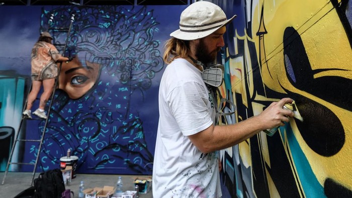 Dua seniman membuat gambar grafiti dengan media tembok saat festival grafiti bertajuk Meeting of Styles (MOS) di Pulosari, Kebakkramat Jawa Tengah, Sabtu (31/5/2025). Acara yang juga diisi dengan bazar seni, pameran hip-hop dan Realitas Virtual grafiti tersebut diikuti 65 seniman grafiti dari 15 negara guna mengedukasi masyakarat dan mengangkat potensi pariwisata berbasis sei grafiti. ANTARAFOTO/Maulana Sury/Spta. *** Local Caption ***