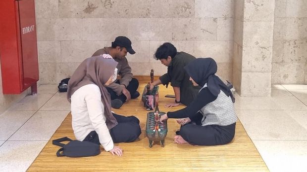 Pengunjung bermain dakon atau congklak TMII