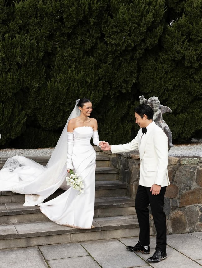 Tampil serba putih, Amanda terlihat cantik dan elegan. Ia juga memilih hand bouquet berisi bunga berwarna putih. Ditambah dengan riasan natural glam yang flawless dan rambut simple bun, penampilannya jadi terkesan simpel namun tetap memukau. Foto: Instagram/@amandarawles