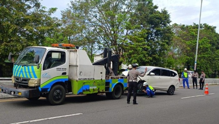 Polisi dan petugas tol mengevakuasi mobil yang terbalik di Makassar.