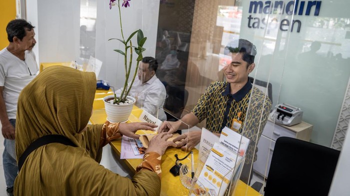 Petugas melayani peserta Taspen saat mengambil gaji pensiun di KCP Mandiri Taspen Rawamangun, Jakarta, Senin (2/6/2025). PT Taspen (Persero) mulai menyalurkan gaji ketiga belas Tahun 2025 kepada para penerima pensiun dan tunjangan yang merupakan wujud komitmen Taspen dalam meningkatkan kesejahteraan para aparatur sipil negara purnabakti mulai 2 Juni 2025. ANTARA FOTO/Bayu Pratama S/agr