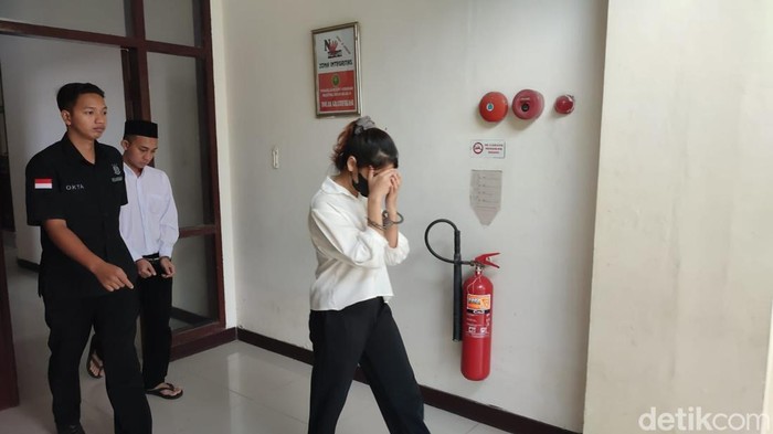 Ichlas dan Viska saat berjalan menuju ke ruang sidang tempat mereka menjalani sidang tuntutan di Pengadilan Negeri Gresik.