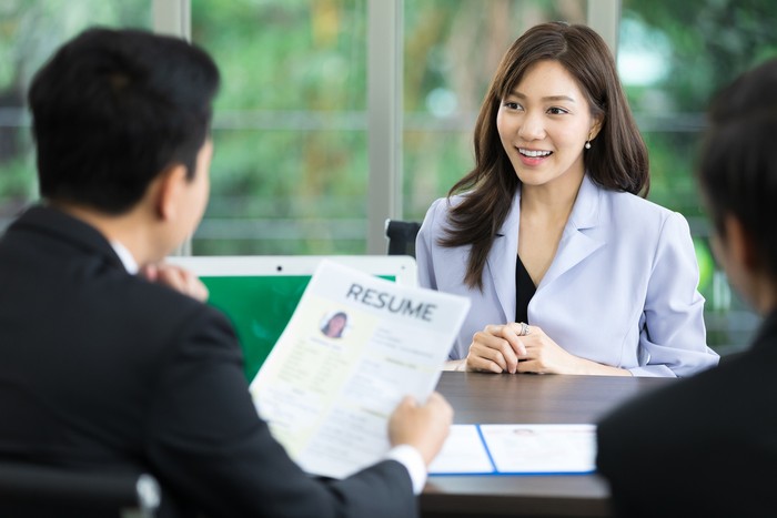 hr officer holding resume at job interview, considering woman employee candidature for open work position
