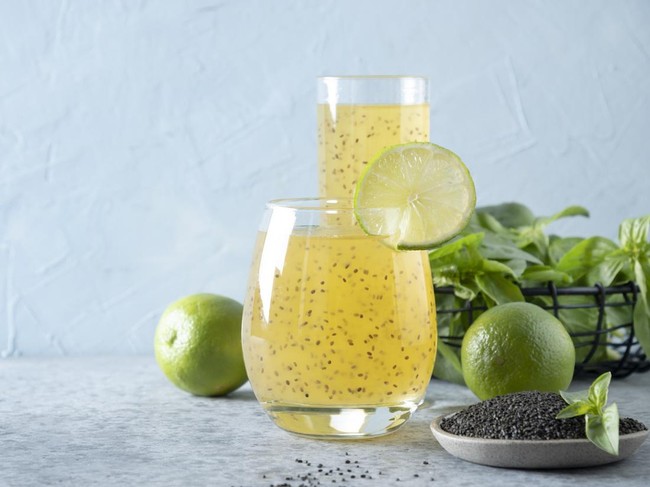 Basil seed drink with orange juice in glass on light background. Close up. Healthy detox beverage for lose weight. Space for text.