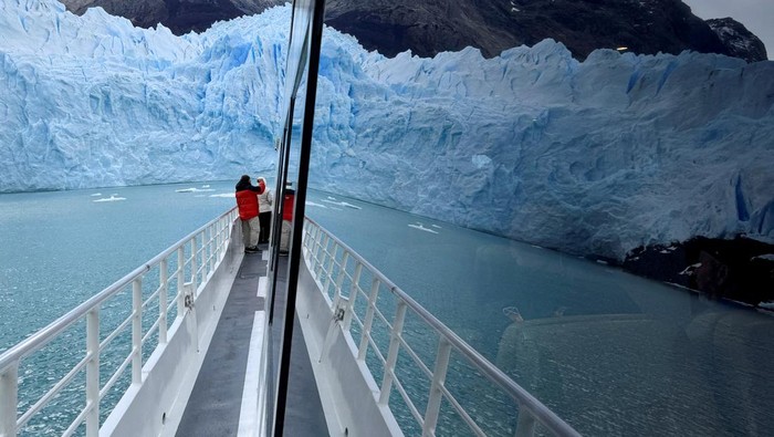 Pecahnya Es Raksasa di Gletser Perito Moreno, Indah tapi Mengkhawatirkan The Perito Moreno glacier is seen reflected in the window of a tourist boat, near the city of El Calafate in the Patagonian province of Santa Cruz, Argentina April 22, 2025. REUTERS/Bernat Parera     TPX IMAGES OF THE DAY