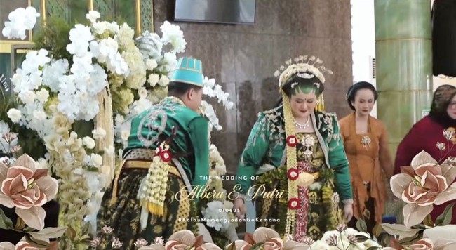 Putri mengenakan busana Solo basahan yang terdiri dari busana dodot yang dikombinasikan dengan kebaya hijau. Bagian kepalanya juga dihiasi dengan paes dan sanggul. Aksesori kepala seperti cunduk mentul hingga ronce melati juga turut dikenakan Putri. Foto: YouTube/Putri Habibie