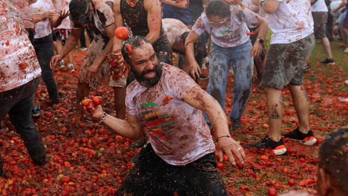 People play with tomato pulp during the annual 
