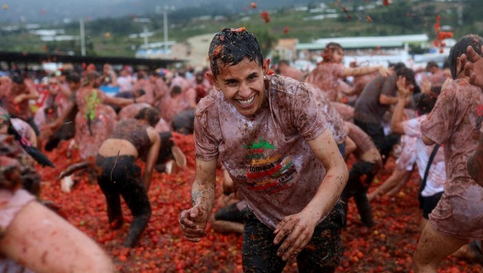People play with tomato pulp during the annual 