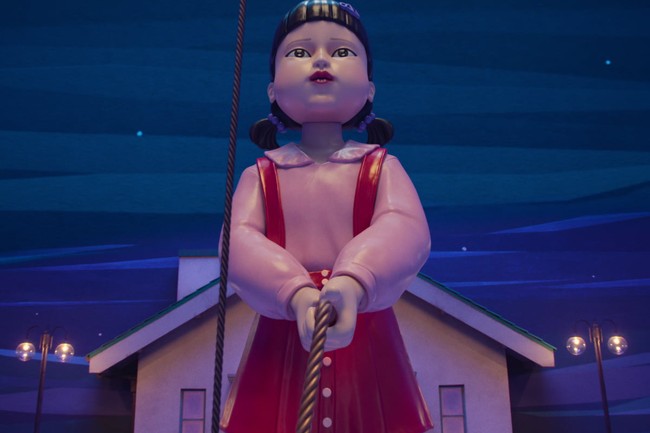 Boneka robot legendaris Squid Game, Young Hee muncul lagi dengan kostum yang lebih mencekam, tidak lagi bernuansa oranye-kuning. Young Hee mengawasi pergerakan peserta dengan mata laser-nya dan memegang tali raksasa. Squid Game 3 akan segera tayang di Netflix pada 27 Juni 2025. Foto: dok. Netflix