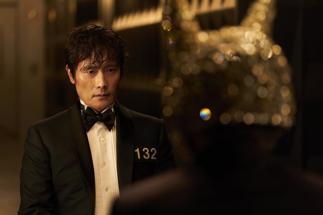 Front Man (pemain Lee Byung Hun) berhasil mengelabui Seong Gi Hun setelah menyusup sebagai peserta permainan bertahan hidup. Tampil memakai setelan jas hitam. Dalam trailer drama Korea Squid Game 3, dia menanyakan apakah Seong Gi Hun masih percaya dengan manusia. Foto: dok. Netflix