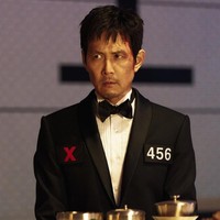 Pemain utama drama Korea Squid Game 3, Lee Jung Jae kembali sebagai Seong Gi Hun. Dalam bocoran foto yang dirilis, dia tampak mengenakan setelan jas hitam dan memberikan tatapan dingin kepada seseorang. Akankah Seong Gi Hun mampu menghentikan permainan bertahan hidup itu untuk selamanya? Foto: dok. Netflix