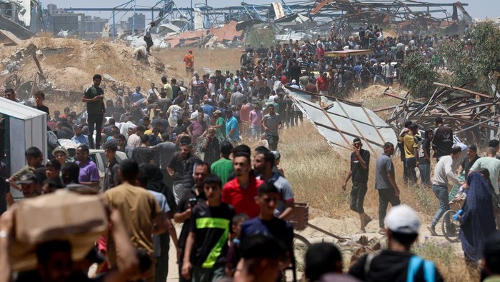 Palestinians walk with aid supplies which they received from the U.S.-backed Gaza Humanitarian Foundation, in the central Gaza Strip, May 29, 2025. REUTERS/Ramadan Abed REFILE - CORRECTING LOCATION FROM 
