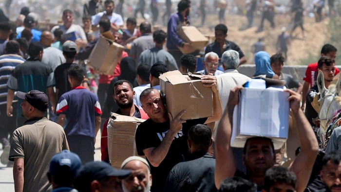 Palestinians walk with aid supplies which they received from the U.S.-backed Gaza Humanitarian Foundation, in the central Gaza Strip, May 29, 2025. REUTERS/Ramadan Abed REFILE - CORRECTING LOCATION FROM 