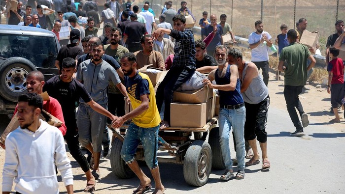 Palestinians walk with aid supplies which they received from the U.S.-backed Gaza Humanitarian Foundation, in the central Gaza Strip, May 29, 2025. REUTERS/Ramadan Abed REFILE - CORRECTING LOCATION FROM 