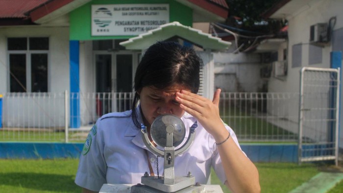 An officer observing a solar radiation duration measuring device (Campbell Stokes) at an open laboratory in Medan, North Sumatra.