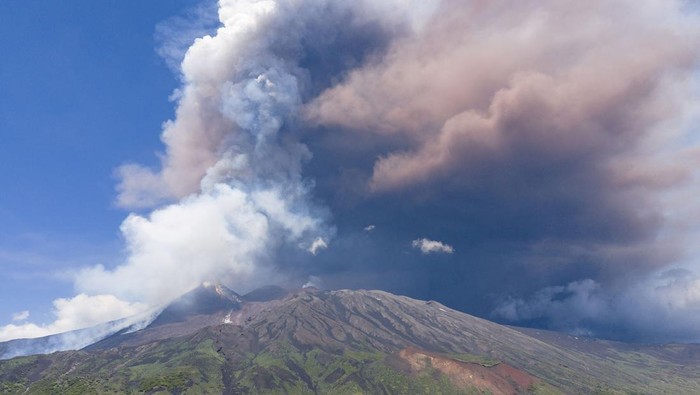 People watch as plumes of volcanic ash rise from Mount Etna, as seen from Milo, Italy, June 2, 2025. REUTERS/Giuseppe di Stefano