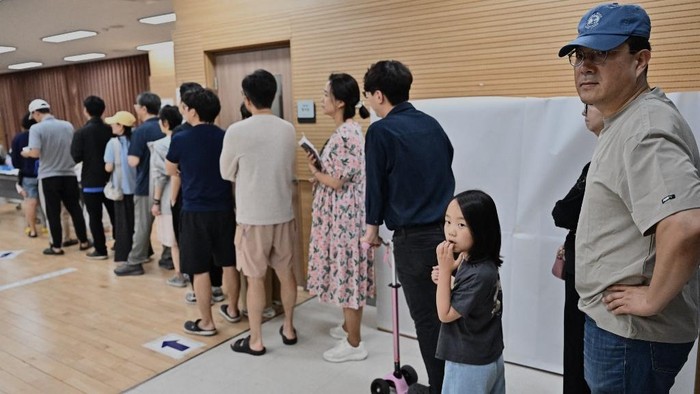 People queue to vote at a polling station during the presidential election in Seoul on June 3, 2025. (Photo by Pedro Pardo / AFP)