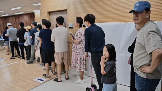 People queue to vote at a polling station during the presidential election in Seoul on June 3, 2025. (Photo by Pedro Pardo / AFP)
