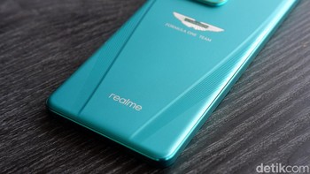 Realme GT 7 Dream Edition tampil memukau dengan warna khas Aston Martin Racing Green yang elegan dan sporty, dilengkapi logo dua sayap ikonik Aston Martin di panel belakang. Desainnya mengusung konsep aerodinamis yang terinspirasi dari lintasan balap F1, dengan material kaca matte dan bingkai metal premium. Foto: Adi Fida Rahman/detikINET