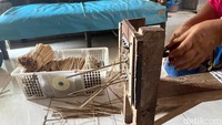 Perajin bernama Tumiarsih (63) menancapkan bilah bambu ke lubang alat serut tradisional. Setelah 12 lubang terisi, ia menariknya satu per satu dari sisi belakang menggunakan tang. Seketika bilah bambu menjadi lebih halus dan rapi.