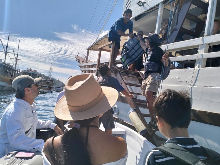 Wisatawan korban penipuan travel agent di Labuan Bajo turun dari pinisi seusai menyelesaikan trip di kawasan TN Komodo, Manggarai Barat, Rabu (4/6/2025). (Ambrosius Ardin/detikBali)
