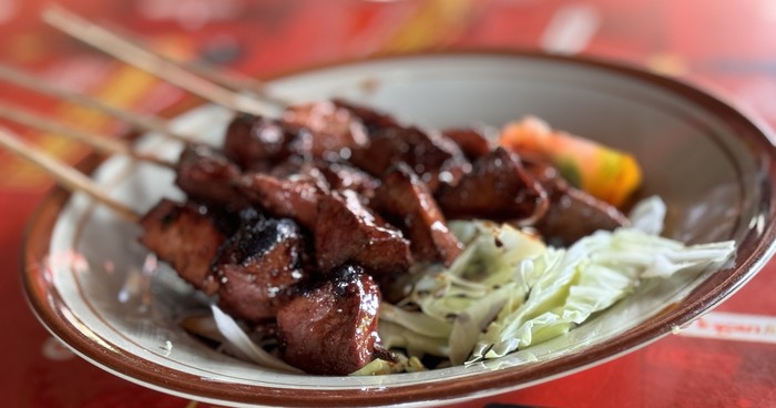 Sate kambing or lamb satay or goat meat satay served with sliced cabbage, tomatoes, sweet soy sauce and chilli, Indonesian street food