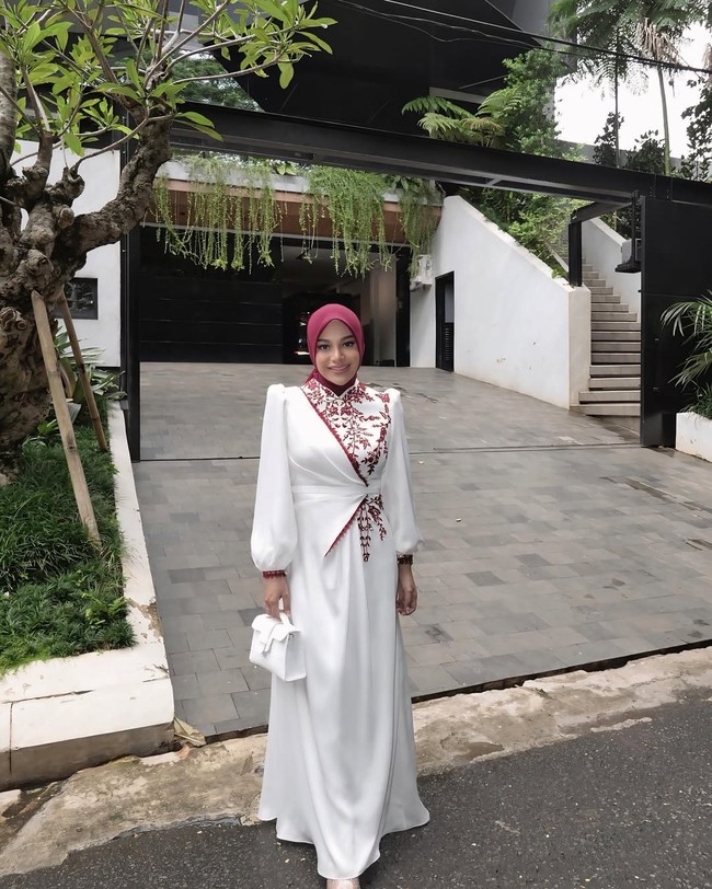 Dalam acara tasyakuran kehamilan adik iparnya, Aurel mengenakan gamis putih mewah dengan aksen bordir merah dan hijab merah marun, tampil anggun dan berkelas.  Foto: Dok. Instagram @aurelie.hermansyah.