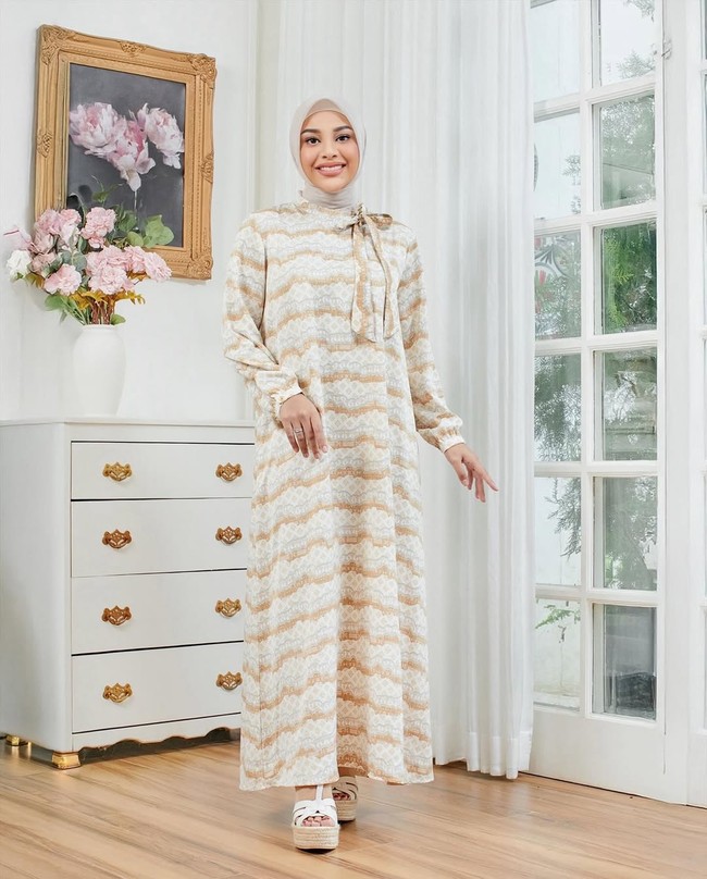 Ibu dua anak ini tampil manis dengan gamis modern bernuansa pastel yang dipadukan dengan hijab segi empat polos warna nude, cocok untuk wanita usia 20-an. Foto: Dok. Instagram @aurelie.hermansyah.
