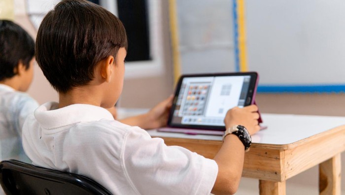 boy using digital device in school classroom.