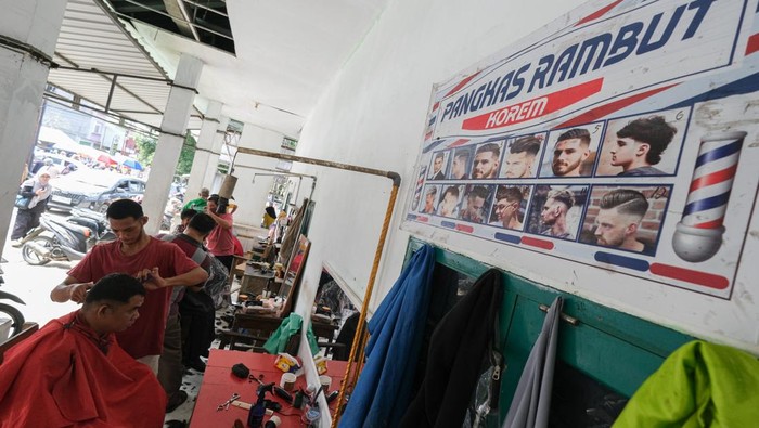 Dua orang tukang pangkas rambut melayani pelanggan di kios cukur rambut di kawasan Korem, Kendari, Sulawesi Tenggara, Kamis (5/6/2025). H-1 menjelang hari raya Idul Adha, jumlah pelanggan yang datang untuk memangkas rambut di kawasan tersebut meningkat sebanyak 100 persen dibandingkan tahun lalu dan hari biasanya dengan tarif Rp30 ribu per orang. ANTARA FOTO/Andry Denisah/bar