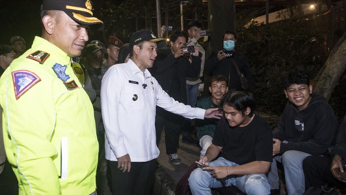 Pelajar Bandung Dilarang Keluyuran Lewat Jam 9 Malam Wakil Wali Kota Bandung Erwin (kedua kiri) didampingi Kapolrestabes Bandung Kombes Pol Budi Sartono (kiri) menyampaikan edukasi dan imbauan kepada warga saat patroli jam malam pelajar di Bandung, Jawa Barat, Rabu (4/6/2025). Pemerintah Kota Bandung mulai memberlakukan aturan jam malam dari Gubernur Jawa Barat tentang pelarangan aktivitas bagi pelajar atau peserta didik di luar rumah mulai pukul 21.00 WIB hingga 04.00 WIB.  ANTARA FOTO/Novrian Arbi/nz