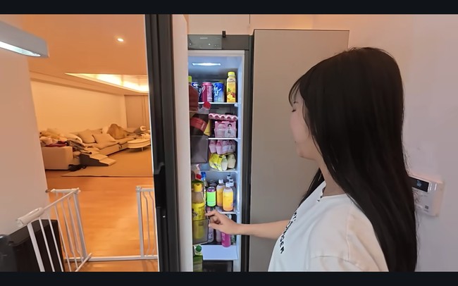 Kulkas kedua Tzuyang terlihat lebih rapi dan diletakkan di tengah rumahnya, khusus untuk menyimpan minuman kemasan. Sekilas tampak desain rumah yang spacious dan minimalis. Sebuah sofa melintang di ruang TV dengan pencahayaan hangat. Foto: dok. YouTube @v-tzuyang