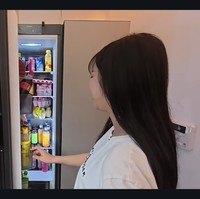 Kulkas kedua Tzuyang terlihat lebih rapi dan diletakkan di tengah rumahnya, khusus untuk menyimpan minuman kemasan. Sekilas tampak desain rumah yang spacious dan minimalis. Sebuah sofa melintang di ruang TV dengan pencahayaan hangat. Foto: dok. YouTube @v-tzuyang