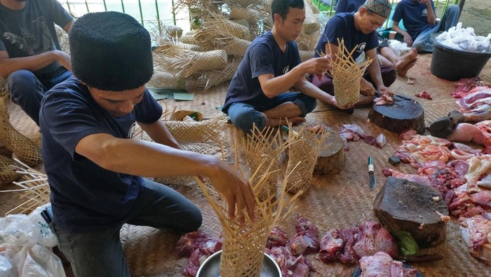 Petugas memasukkan daging kurban ke dalam brongsong (keranjang bambu) untuk dibagikan ke warga di kompleks Majid Agung Temanggung, Jawa Tengah, Jumat (6/6/2025). Pemerintah setempat menghimbau kepada panitia kurban untuk tidak menggunakan plastik sebagai wadah daging kurban dan menggantinya dengan bahan organik sepeti brongsong dan besek bambu guna mengurangi sampah plastik. ANTARA FOTO/Anis Efizudin/foc.
