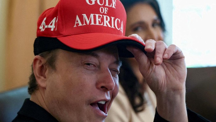 FILE PHOTO: Tesla CEO Elon Musk reacts while wearing a cap with the words 