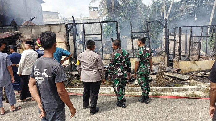 Polisi turun membantu memadamkan kebakaran rumah warga di Kuantan Mudik, Kuansing, Riau.