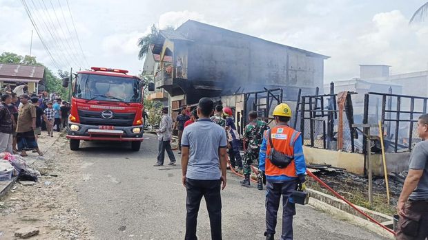 Polisi turun membantu memadamkan kebakaran rumah warga di Kuantan Mudik, Kuansing, Riau.