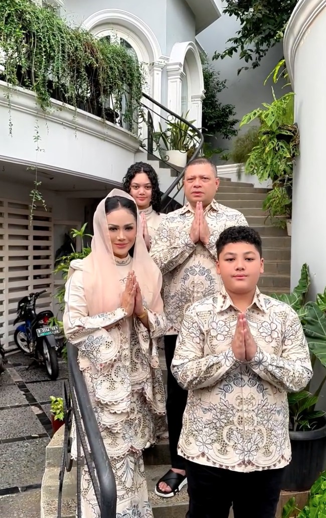 Krisdayanti juga memilih tampil kompak kenakan busana seragam dengan keluarga saat merayakan Idul Adha 2025. Bernuansa nude, Krisdayanti kenakan gamis brokat motif floral lengan panjang. Penampilannya dipadukan dengan kerudung polos yang memberikan kesan kalem dan santun. Foto: Instagram