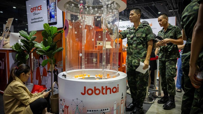 Gaya Para Pencari Kerja di Job Fair Negara Tetangga RI BANGKOK, THAILAND - JUNE 06: Job applicants play a game to win free prizes at the Bangkok Job Expo on June 06, 2025 in Bangkok, Thailand. Job Expo Thailand 2025, Thailand's largest career fair, is being held at the Queen Sirikit National Convention Center. Organized by the Ministry of Labour, the event offers more than 600,000 jobs, including positions for new graduates, people with disabilities, and the elderly, amid growing concerns about economic stagnation and employment security. The fair features over 170 recruiters and workshops to help job seekers build new skills. (Photo by Lauren DeCicca/Getty Images)