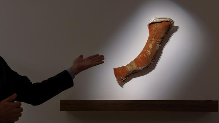 A person gestures at Napoleon Bonaparte's sleeve from his red velvet suit ahead of Sotheby's auction in Hong Kong, China May 23, 2025. REUTERS/Tyrone Siu
