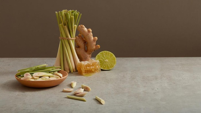 A ginger, a lemon slice and many lemongrass are displayed on minimalist background with a beeswax. Blank space to add text or promote product. Herbals can improve hair and skin condition