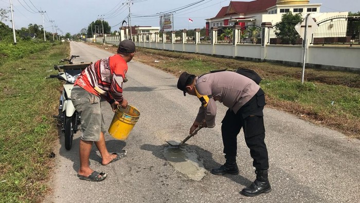 Bhabinkamtibmas di Kecamatan Tebing Tinggi, Kepulauan Meranti, Riau, menutup jalan rusak dengan semen untuk mencegah korban.