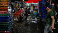 Orang-orang membawa peti untuk memuat buah dari truk di Pasar Long Bien, salah satu pasar grosir terbesar di Hanoi, Vietnam. Foto: REUTERS/Chalinee Thirasupa