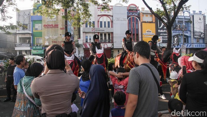 Warga berfoto bareng polisi berkuda di CFD Depok, Jalan Margonda Raya, Kota Depok, Jawa Barat, Minggu (8/6/2025). Lokasi polisi berkuda terletak di ujung CFD Depok dekat persimpangan Jalan Juanda.