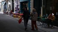 Orang-orang berjalan melewati teras kafe di sebuah jalan di Paris. Foto: REUTERS/Sarah Meyssonnier