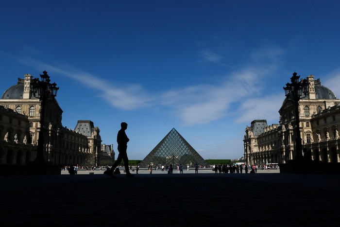 A man walks near the glass Pyramid of the Louvre Museum on a warm sunny spring day in Paris France, May 3, 2025. REUTERS/Gonzalo Fuentes