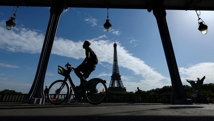 A man rides a bicycle along a bike path on the Pont de Bir-Hakeim bridge near the Eiffel Tower on a warm sunny spring day in Paris, France, May 3, 2025. REUTERS/Gonzalo Fuentes