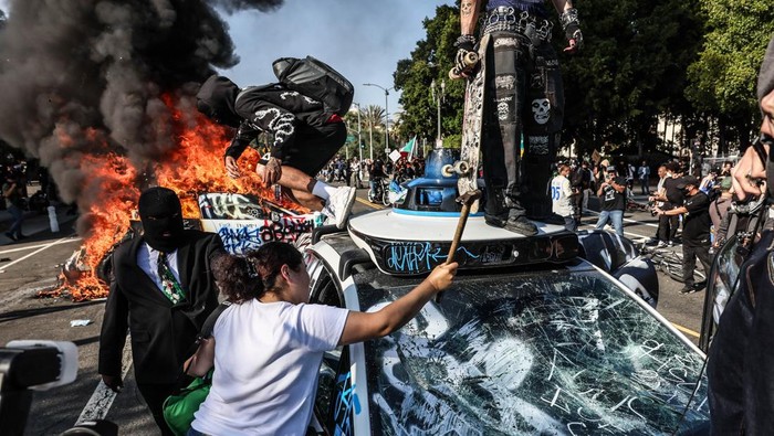 Los Angeles, CA, Sunday, June 8, 2025 - People take turns vandalizing a Waymo taxi as protesters take to the streets to protest ICE immigration raids throughout the city.  (Robert Gauthier/Los Angeles Times via Getty Images)
